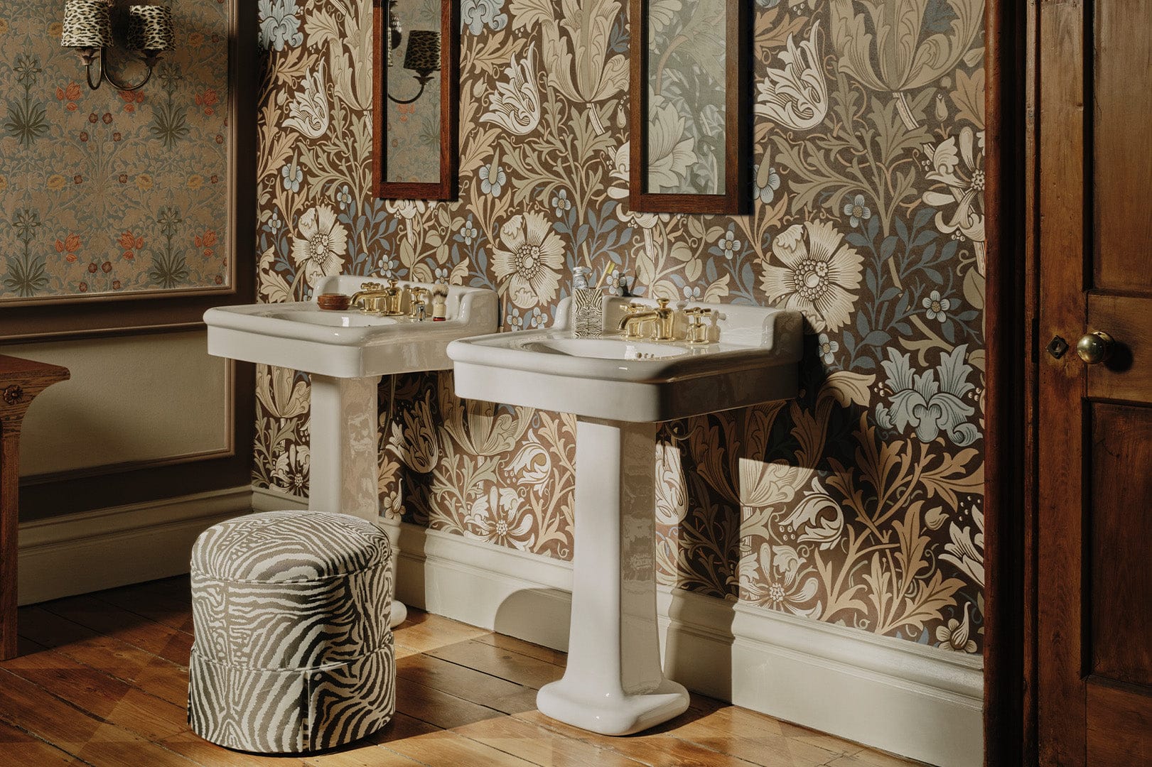 Large-scale floral wallpaper behind two pedestal basins at the House of Hackney showroom.