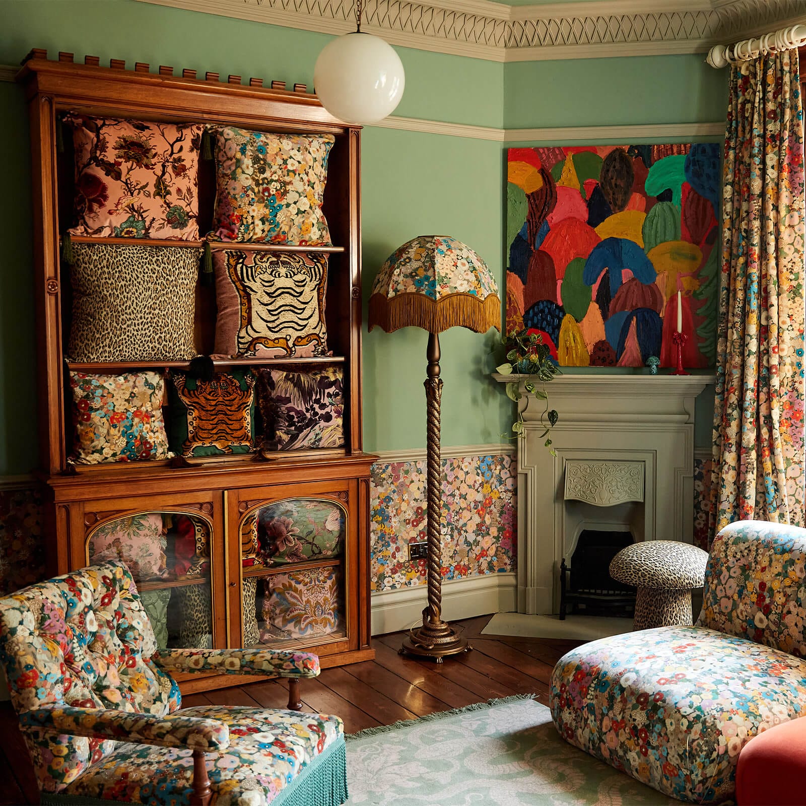 Finished room at the House of Hackney showroom, with patterned wallpaper below the dado, a fireplace and printed armchairs.
