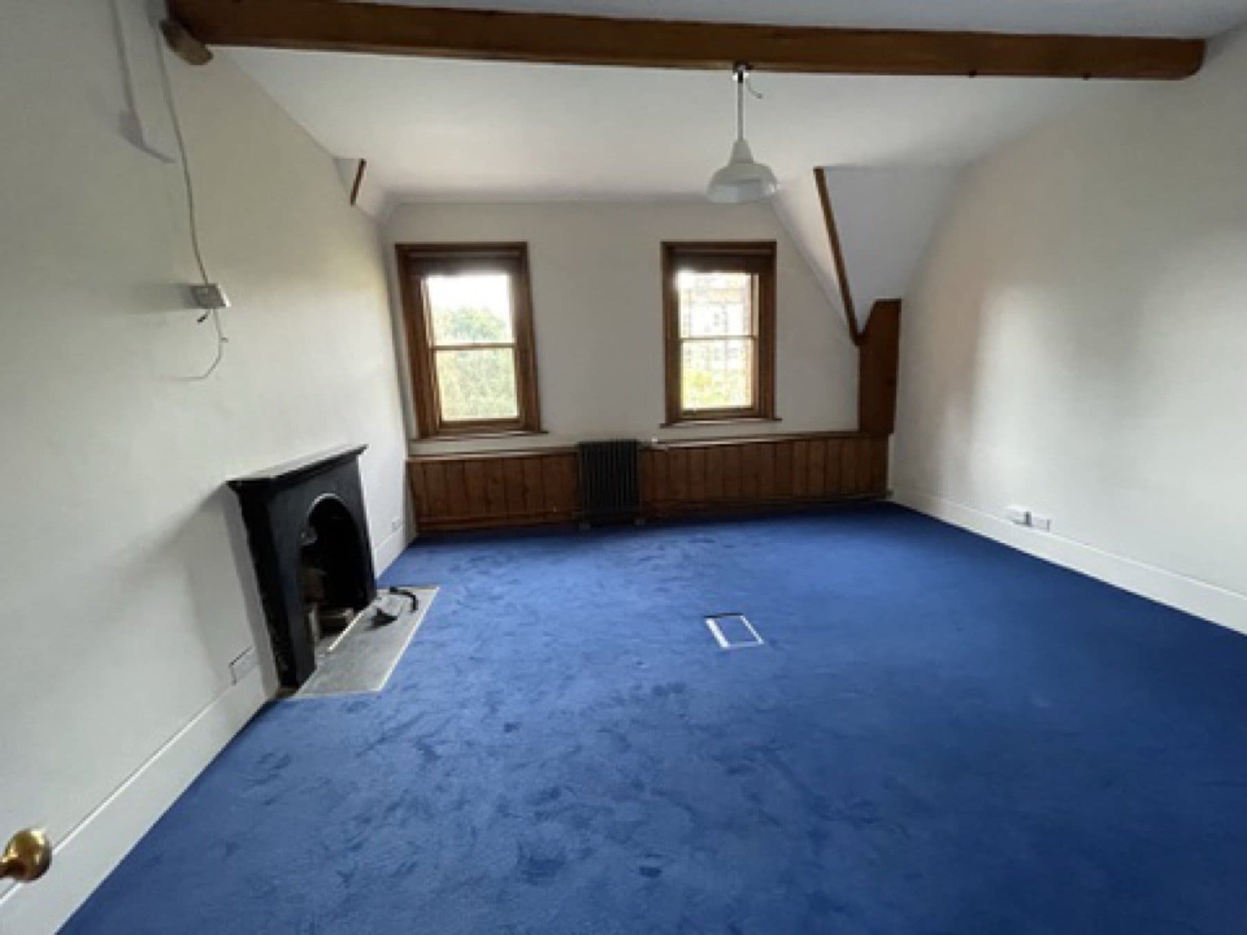 Before: an empty upper room at St Michael's Clergy House, with blue carpet, a fireplace and plain white walls, before the House of Hackney showroom works.