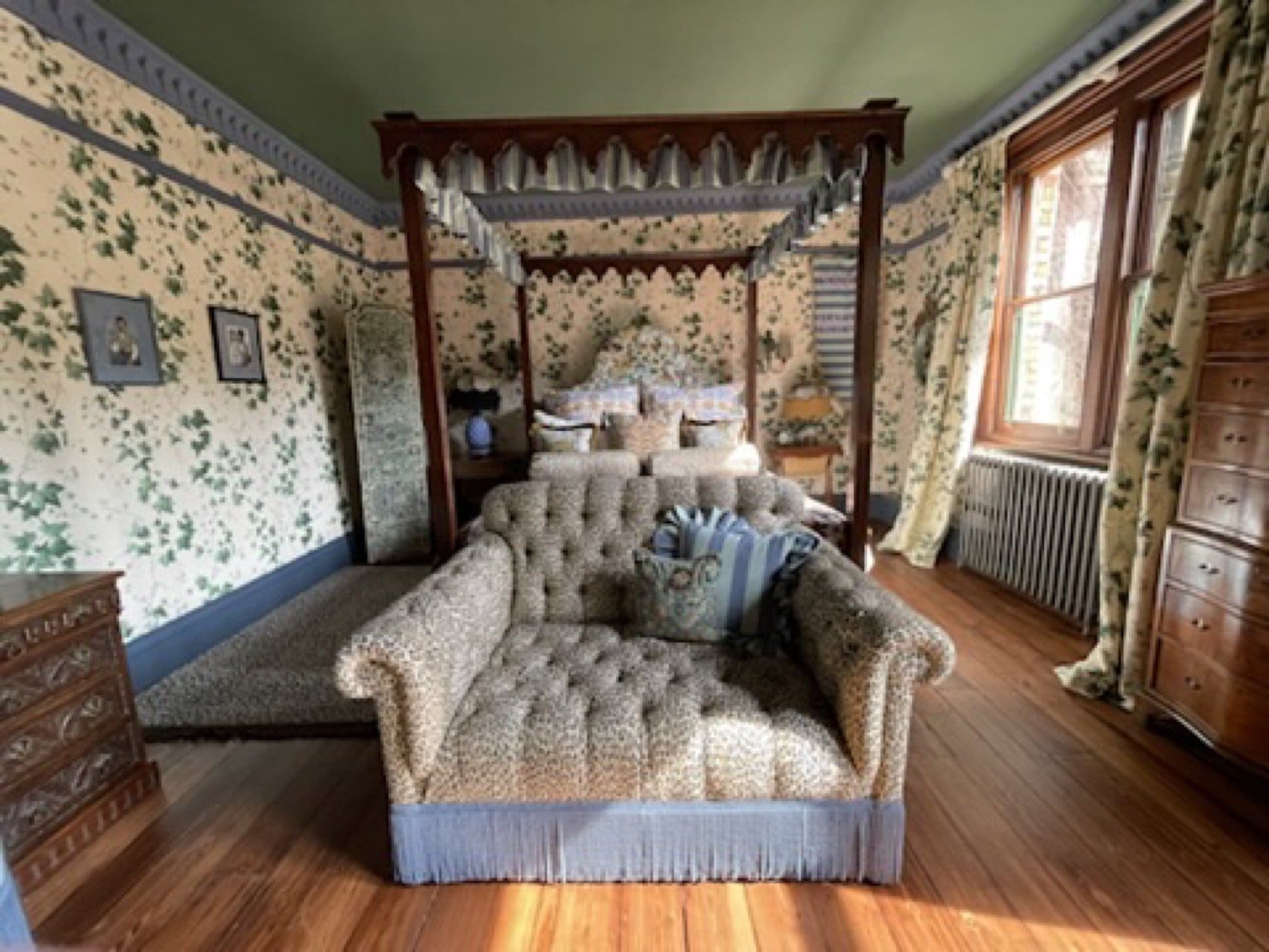 Bedroom set at the House of Hackney showroom, with green floral wallpaper and a four-poster bed.