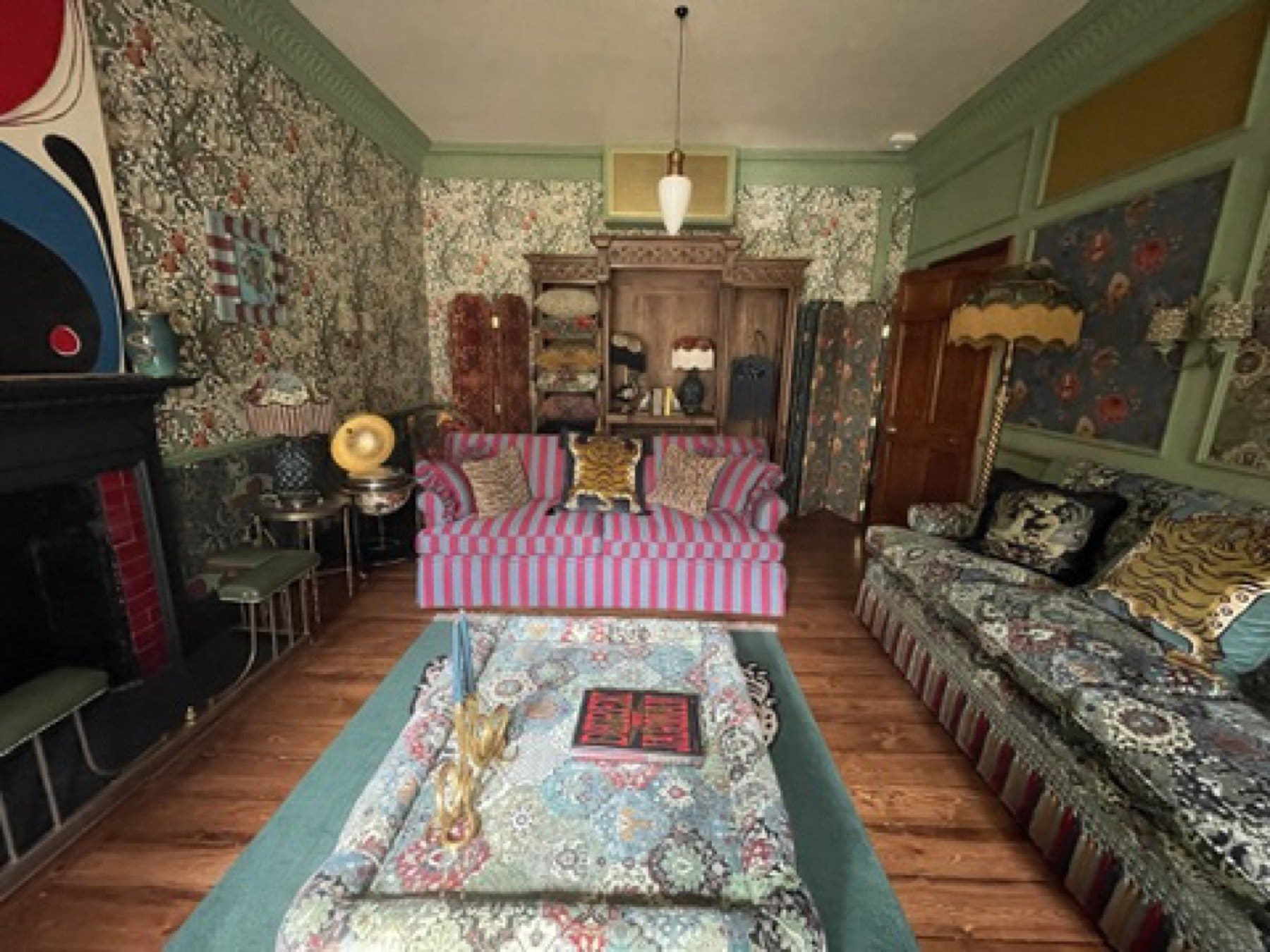 Finished room at the House of Hackney showroom, with floral wallpaper, a fireplace and printed sofas.