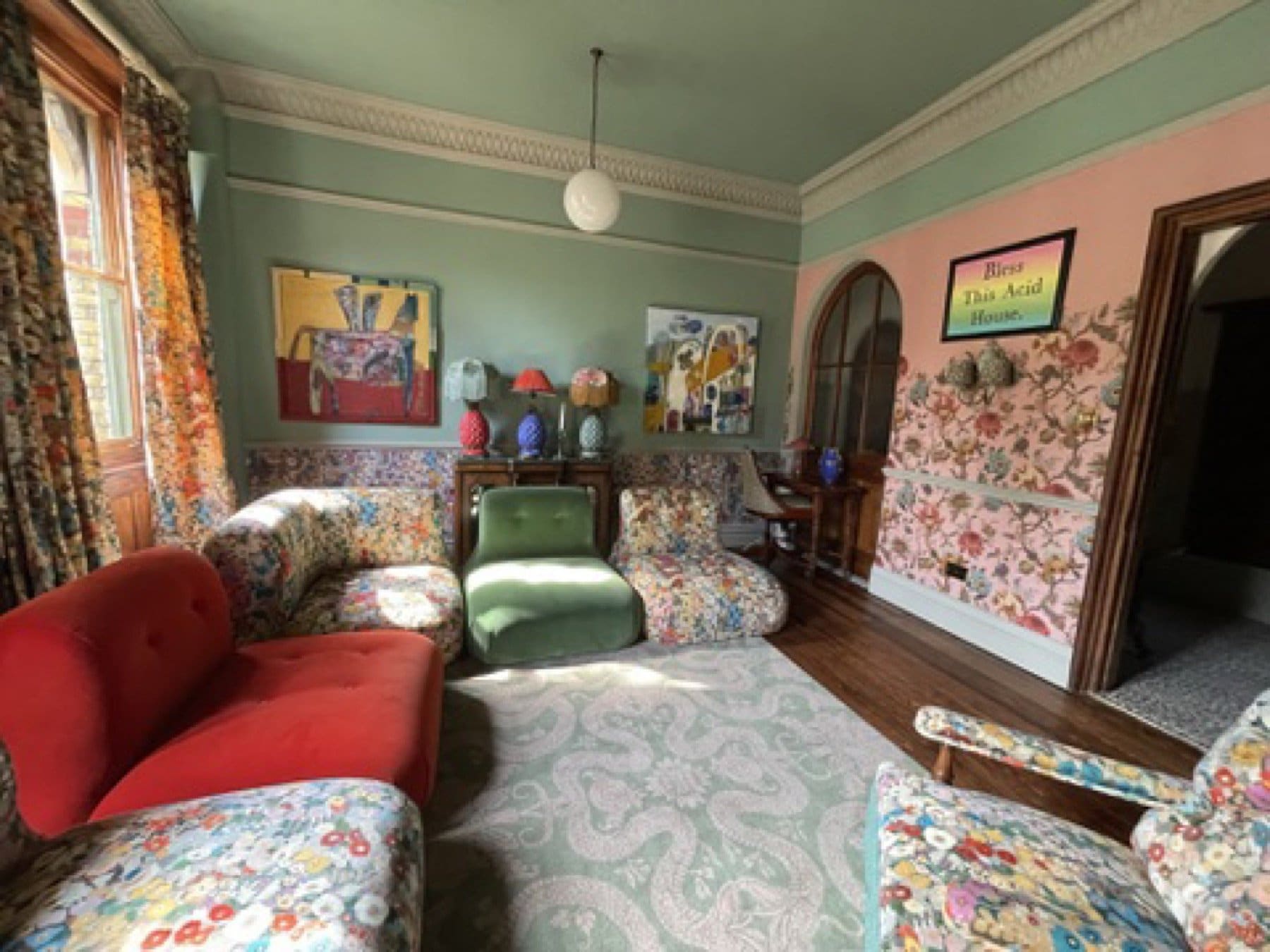 Finished room at the House of Hackney showroom, with green walls, a floral panel and printed sofas.