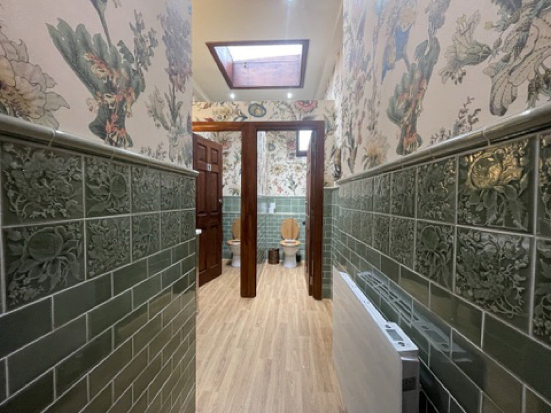 Passage at the House of Hackney showroom, with bird-pattern wallpaper above green tiles.