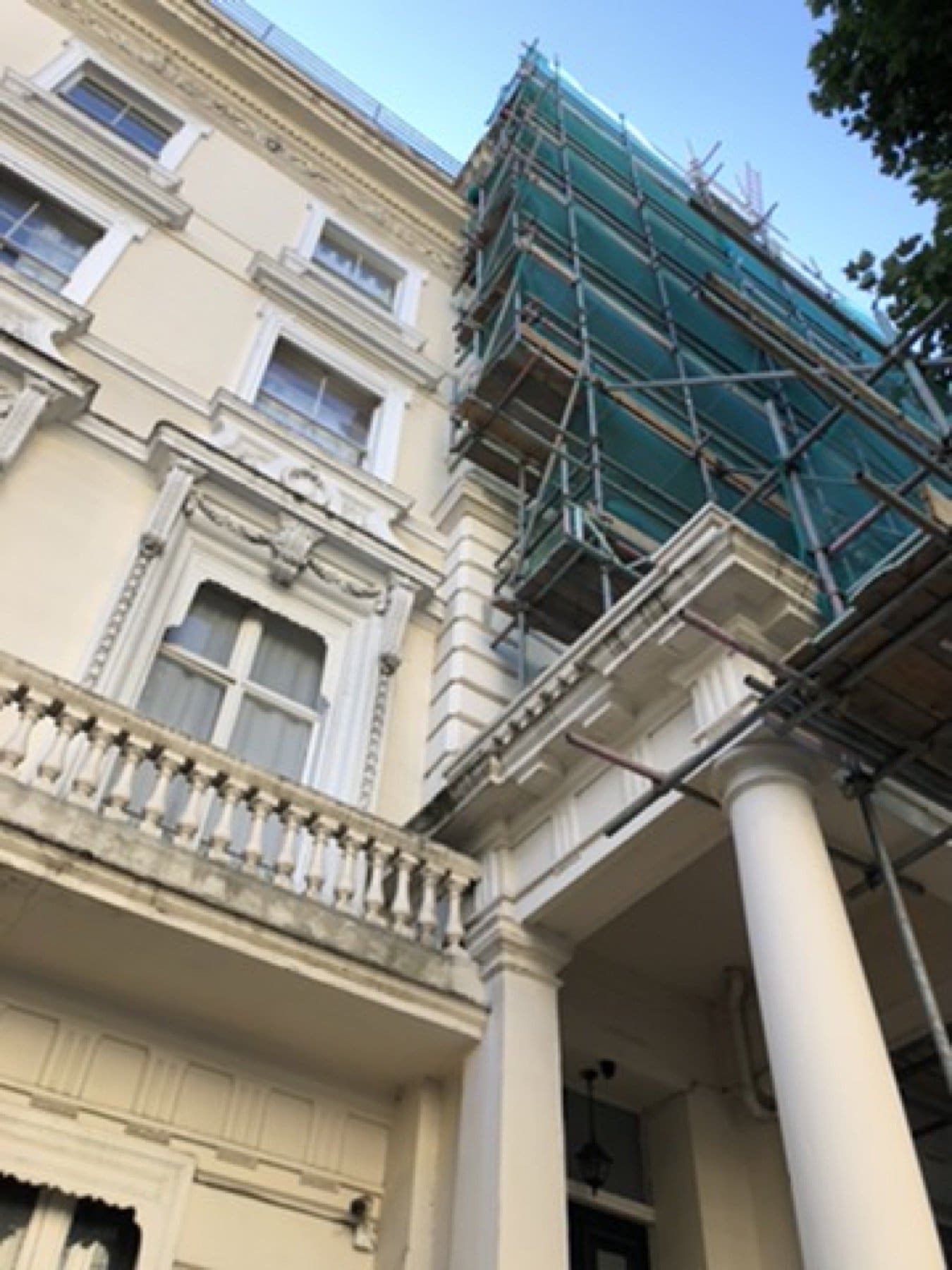 Inverness Terrace front under scaffold netting, with black balcony ironwork and sash windows.