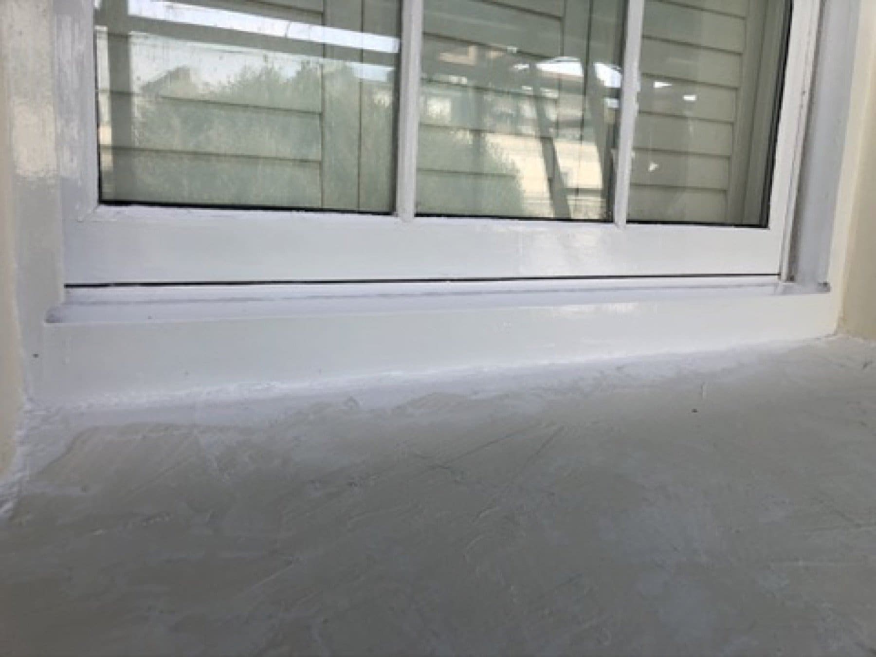 Close view of a sash window and white stucco surround on Inverness Terrace, with scaffold poles in front.
