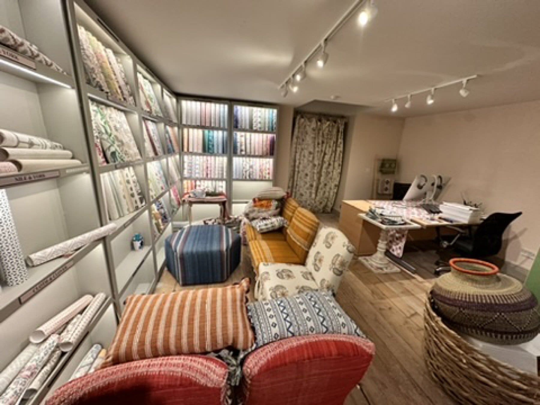 Penny Morrison showroom with floral wallpaper, a fireplace and a patterned red carpet.
