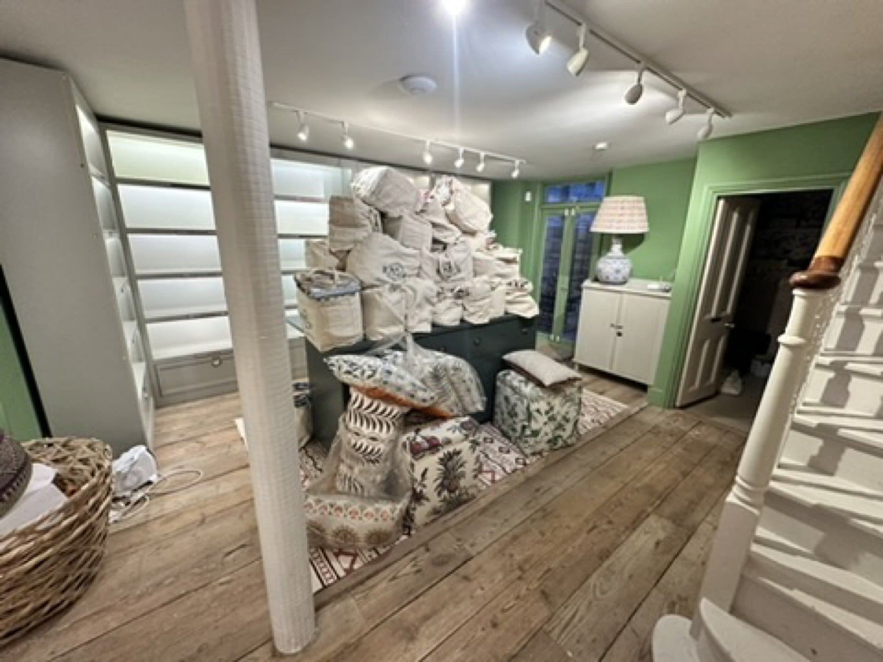 Shelves of fabric samples beside floral wallpaper in the Penny Morrison showroom.