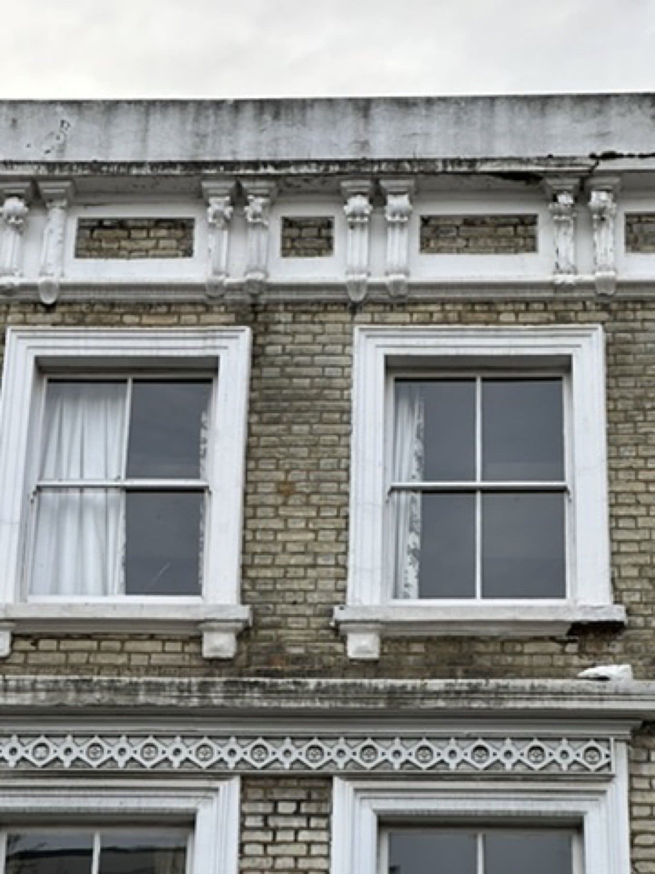 Upper sash windows on the Penny Morrison showroom front, with brick and stucco being prepared.