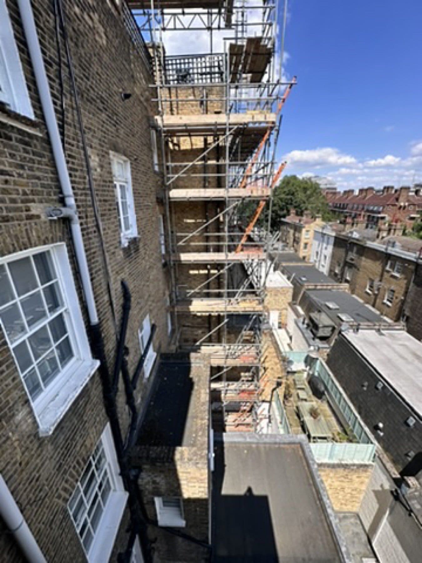 Rear brick elevation on St George's Square, seen from an upper balcony, under scaffold and sheeting.