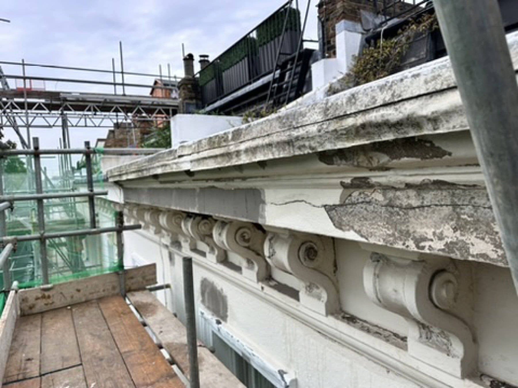 Rear elevation on St George's Square under a full scaffold, red brick and white render, with paint buckets on the boards.