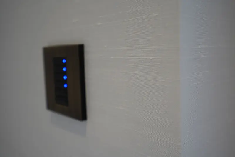Close detail of a textured wallcovering cut neatly around a wall-mounted lighting control.