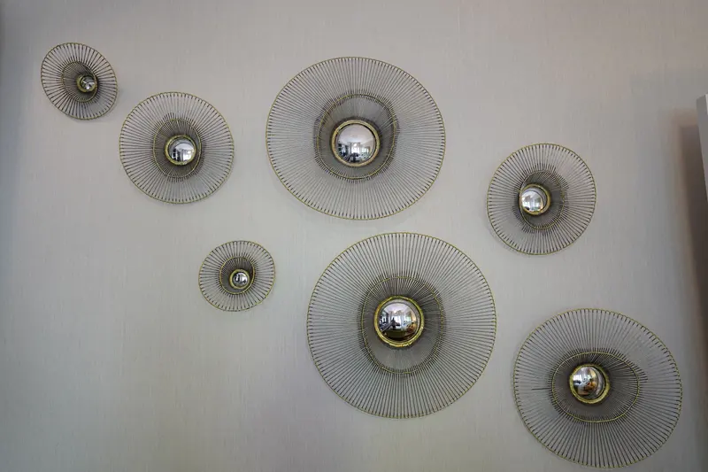 Round wall mirrors with gold radiating frames against a pale wallcovering.