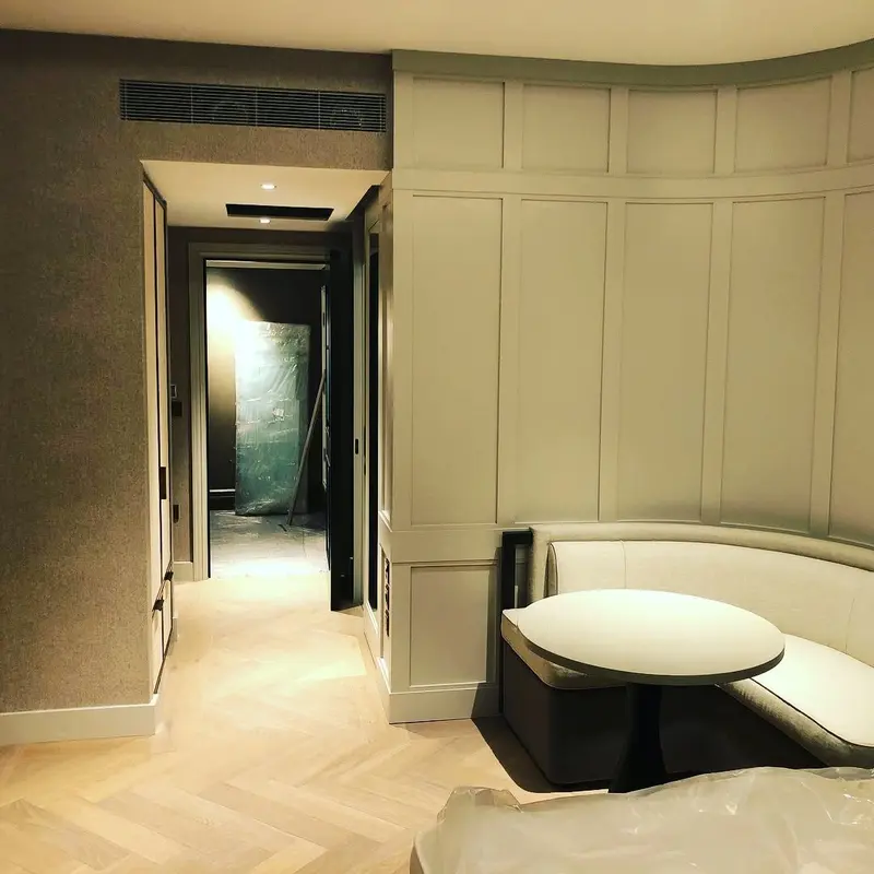 Hotel suite with pale wallcovering, round table and curved banquette seating, the Millennium Hotel, Grosvenor Square, now The Biltmore Mayfair.