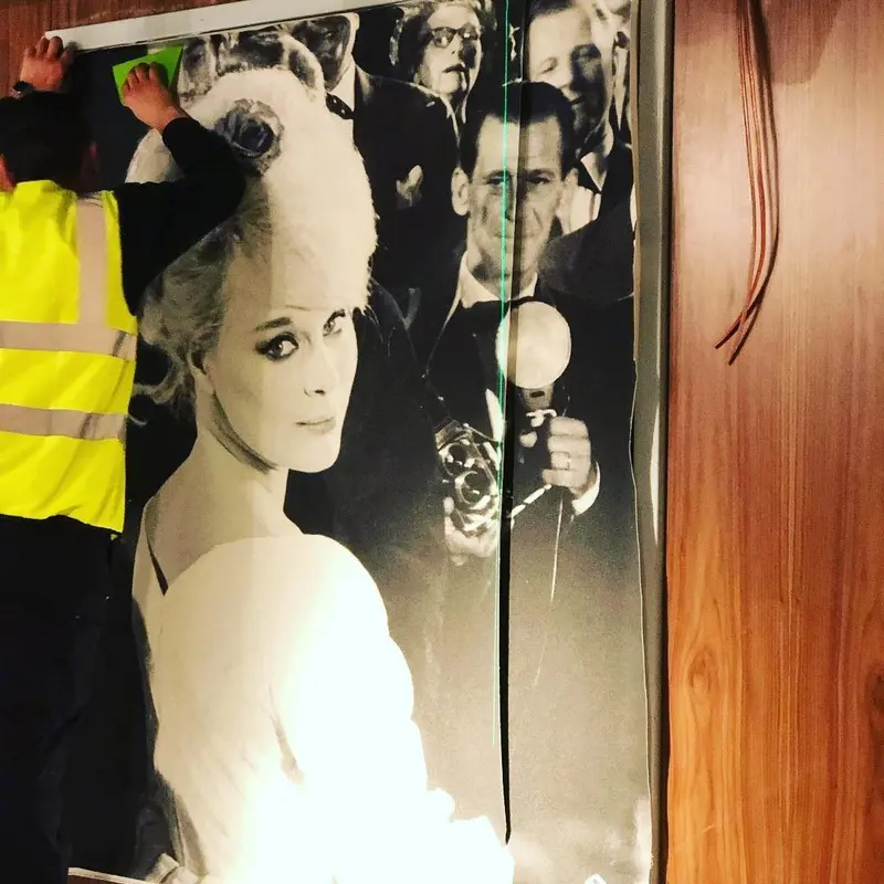 Installer hanging a black-and-white film-star mural, Everyman cinema, Liverpool.