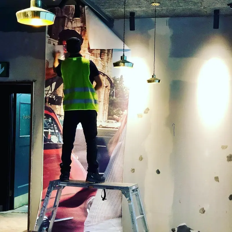 Installer on a platform hanging the mural, Everyman cinema, Liverpool.