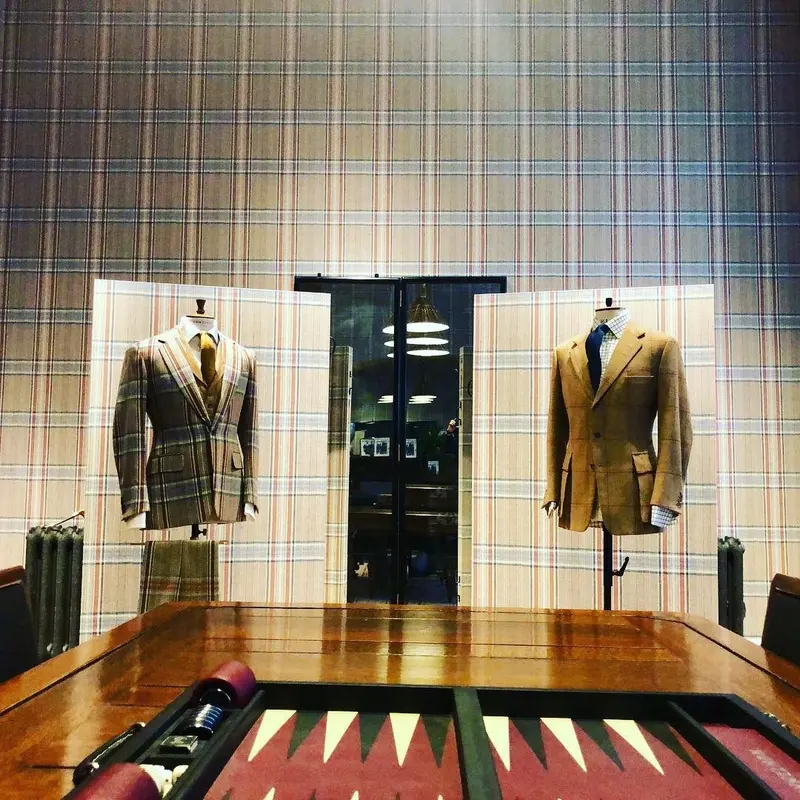 Huntsman, Savile Row: suits displayed on mannequins in front of tweed-print walls.