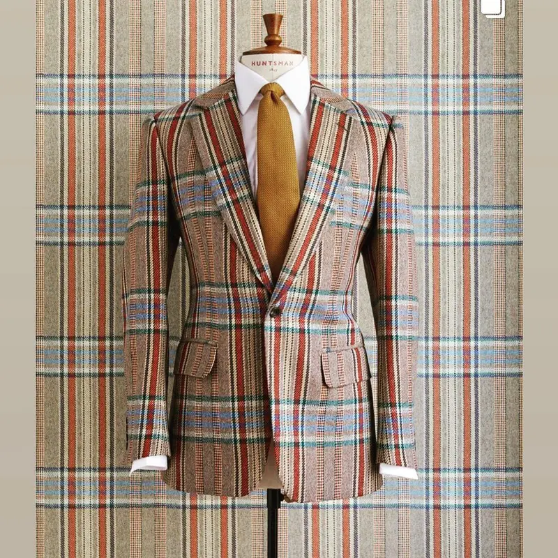 Tweed suit on a mannequin in front of the matching bespoke Huntsman tweed-print wallpaper.