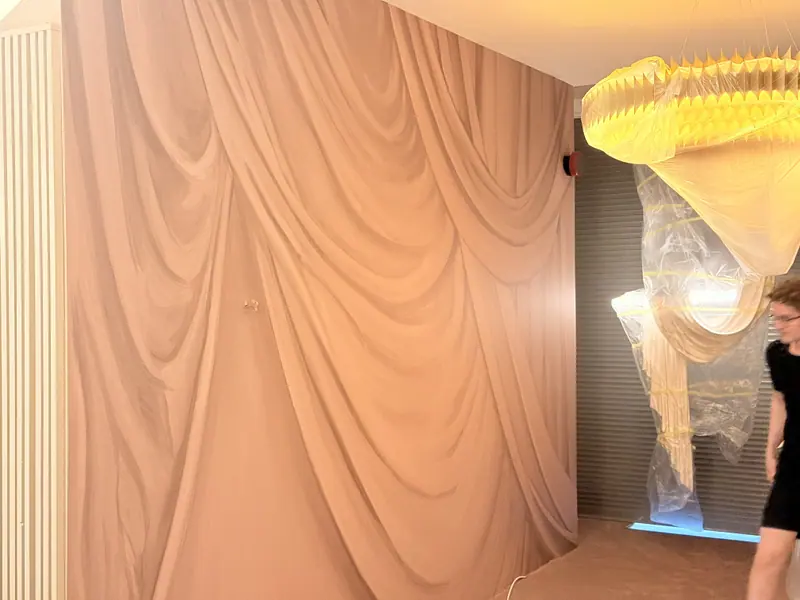 Overture drapery wallpaper beside a chandelier.