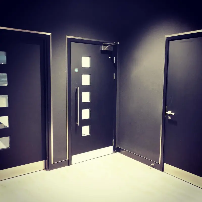 Corridor of black matt wallcovering with steel-trimmed doors and skirting, Mercedes-AMG showroom, London.