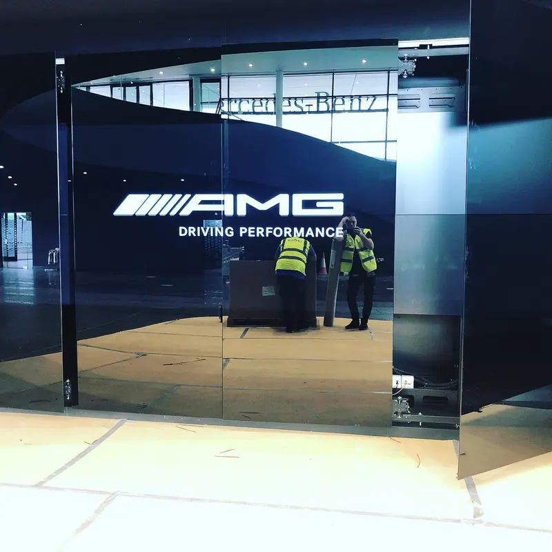 Mercedes-AMG showroom entrance, London, with illuminated AMG branding against the black matt walls.