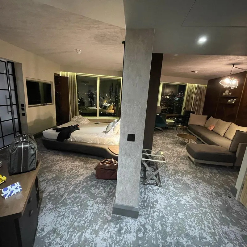 Hotel room with concrete-effect wallcovering on a column, sofa and city view, Novotel London Canary Wharf.