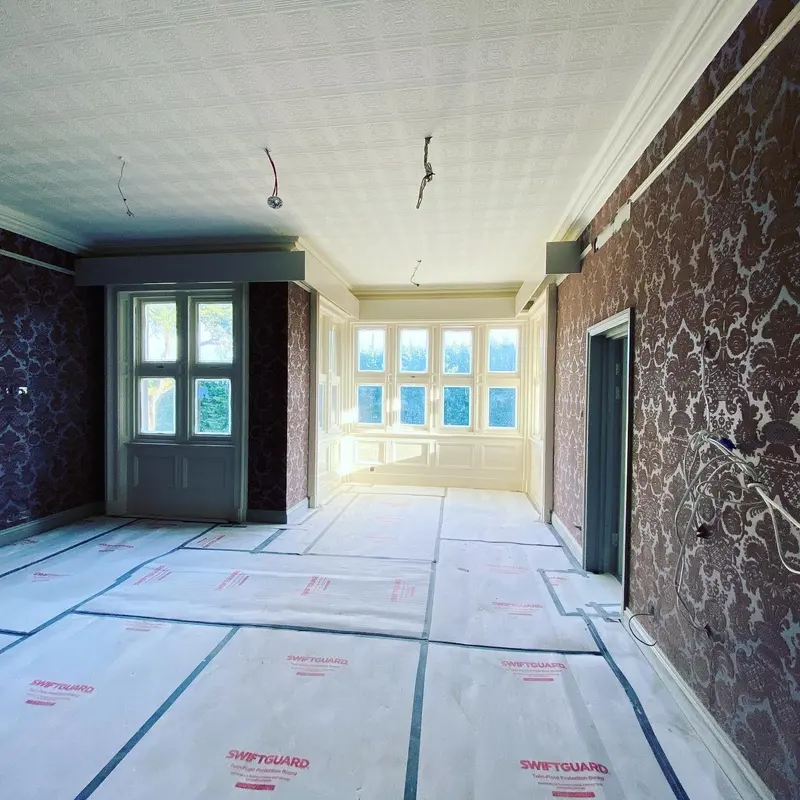 Pendley Manor room papered in dark damask with sash windows, during works.