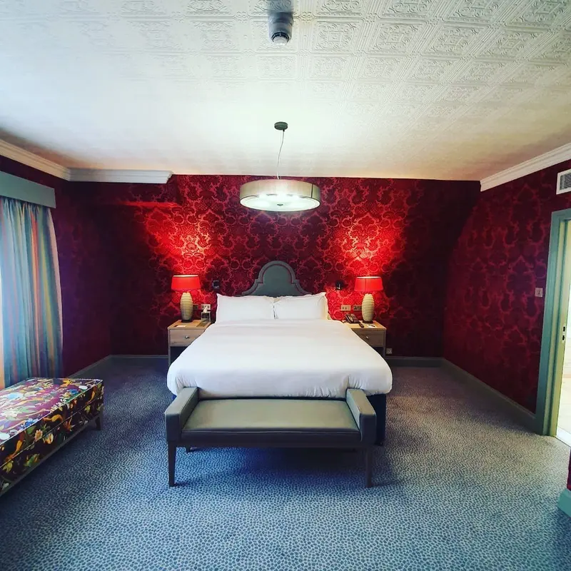 Pendley Manor hotel bedroom with red damask walls and a white bed.