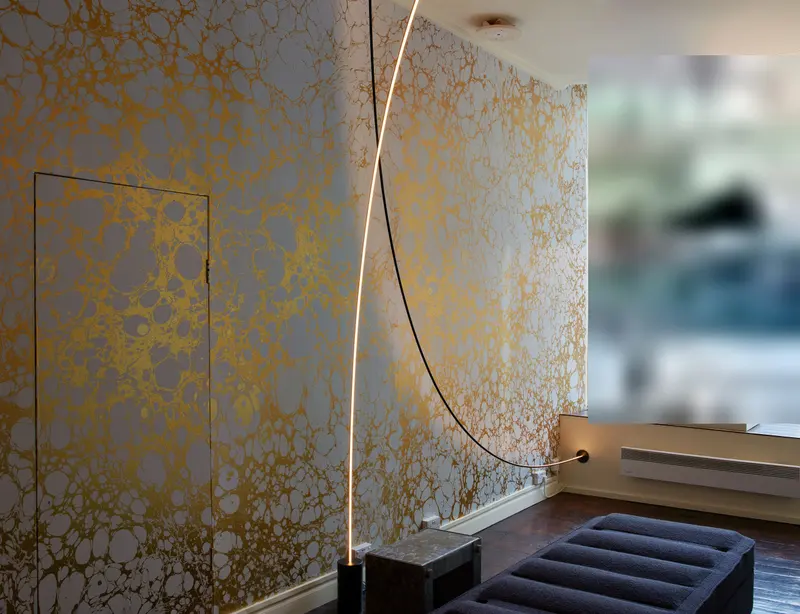 Showroom wall in a gilded marbled wallcovering, a flush door papered in so it almost disappears, beside the shop window.