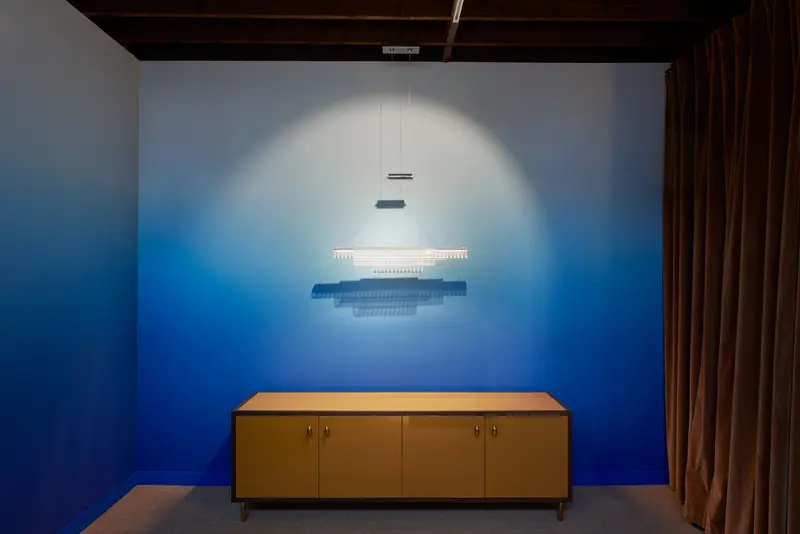 The blue gradient mural behind a low walnut sideboard and a linear light, the colour deepening smoothly to the floor.