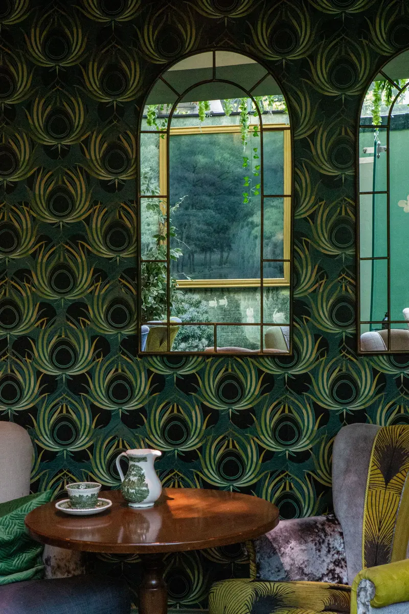 An arched mirror framed by the feather wallpaper, the pattern centred on the mirror and matched across the drops.