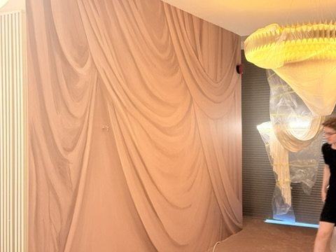 Overture drapery wallpaper beside a chandelier.