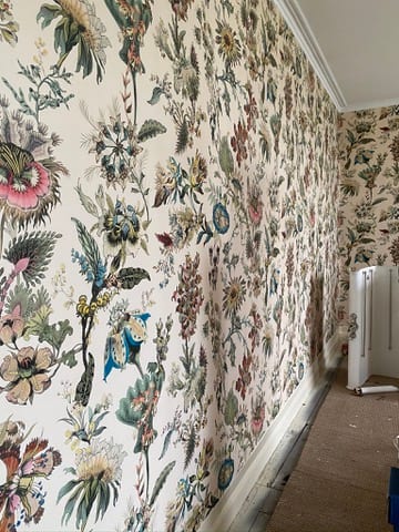 Bedroom at the Castle of Trematon being papered in a pale floral design.
