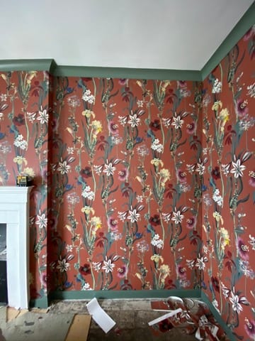 Terracotta floral wallpaper on a fireplace wall at the Castle of Trematon.