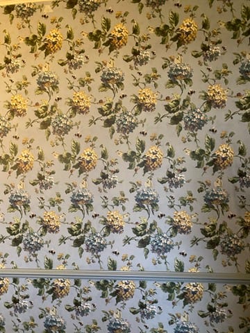 Bedroom at the Castle of Trematon in a large floral wallpaper.