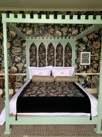 Gothic-style bed against a dark floral wallpaper at the Castle of Trematon.